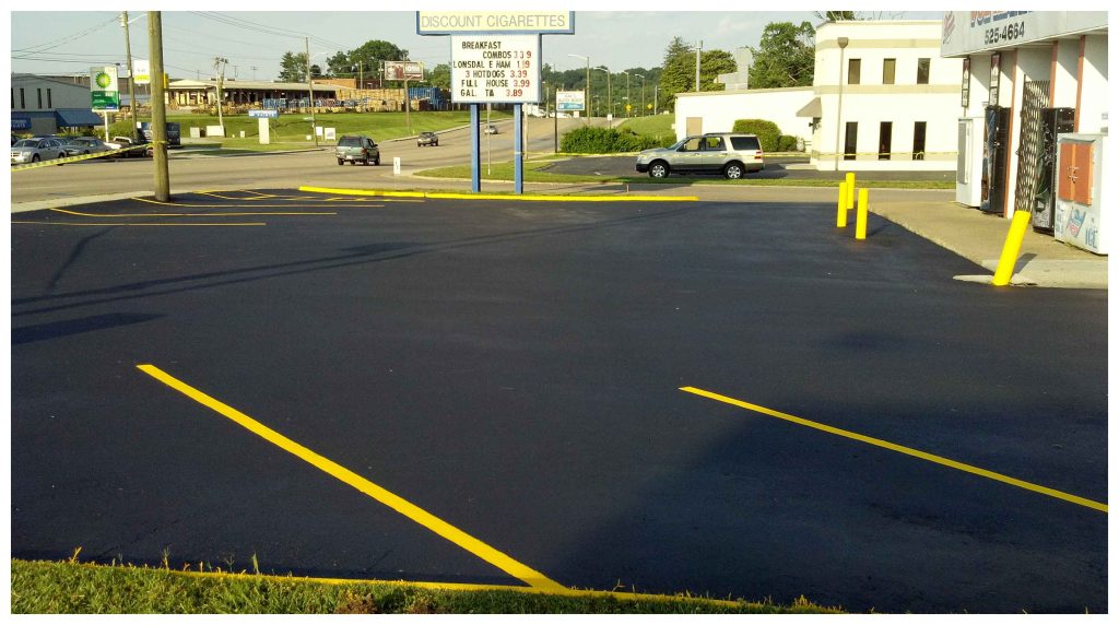 A smooth asphalt driveway entrance with small Mays Paving signs near the road.